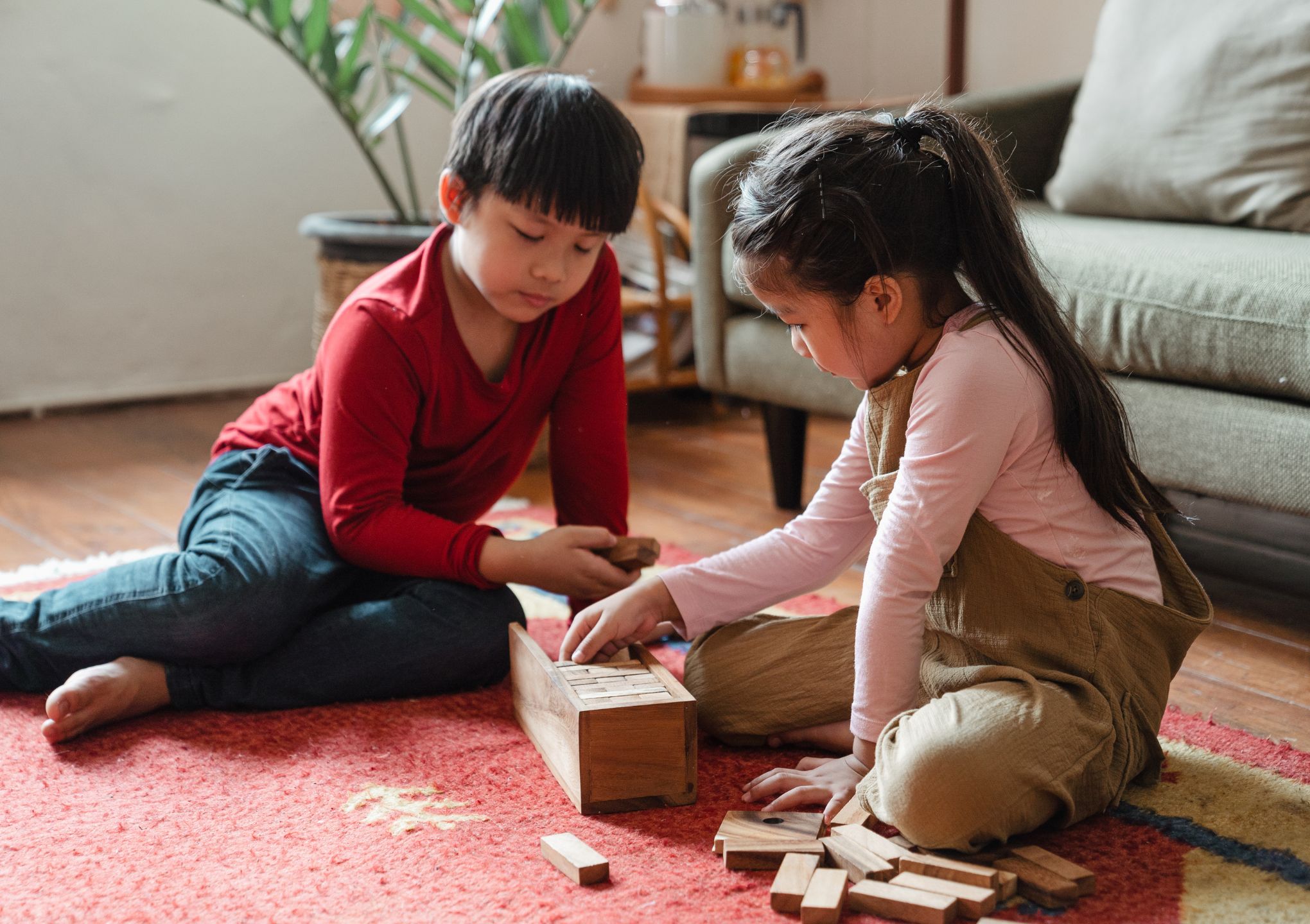 a girl and a boy playing with toys on the carpet of the house - Post Featured Image